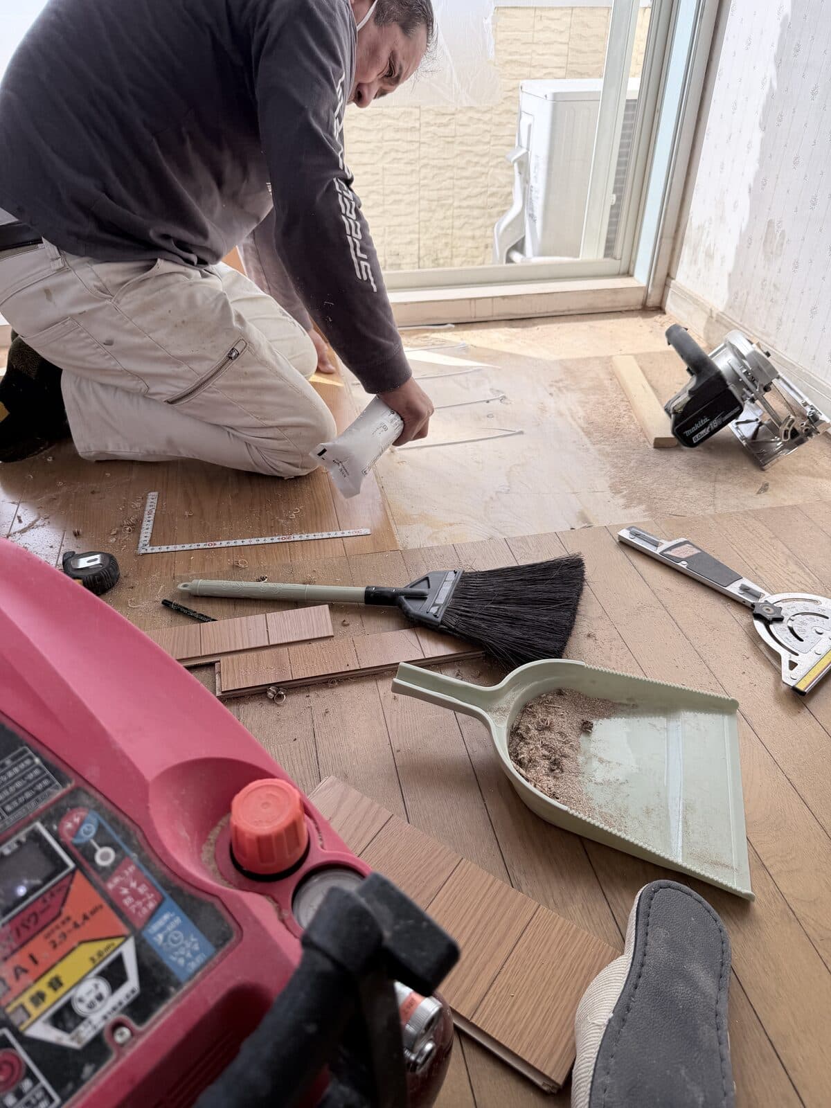 床材を張っている職人と、並べられた道具